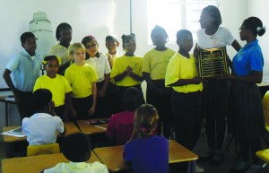 Commonwealth Games athletes, Jonicia Richardson (left) and Renee Fleming (right), present the Commonwealth Sports Day Shield to Yellow House at Teacher Gloria Omololu Institute.