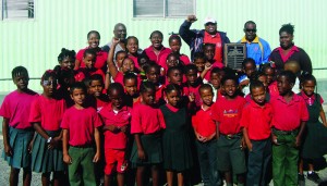 Commonwealth Games team manager, Derrick Carty (left) and athlete, Benjamin Phillips (right), present the Commonwealth Sports Day Shield to Red House at Vivian Vanterpool Primary School.