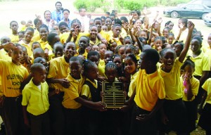 Commonwealth Games athletes, Curlee Gumbs (back-left), Kieron Rogers (back-centre) and Dee-Ann Rogers (back-right), present the Commonwealth Sports Day Shield to Blue House at Valley Primary School.