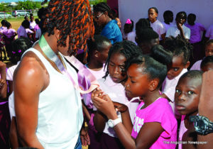 Shara Proctor and Zharnel Hughes addressing students and displaying their 2018 Commonwealth Games Medals